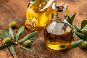 Olivenölflaschen, mit außenrum verziehrenden frischen Oliven